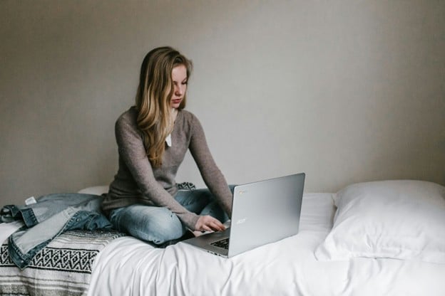 person using laptop on bed