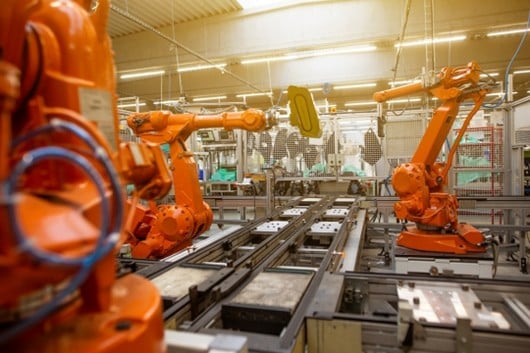 A robotic arm loading a metal part into a CNC machine on a factory floor