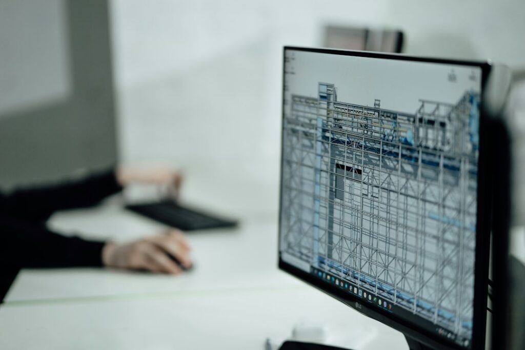 CAD drafter workstation with technical drawings on screen