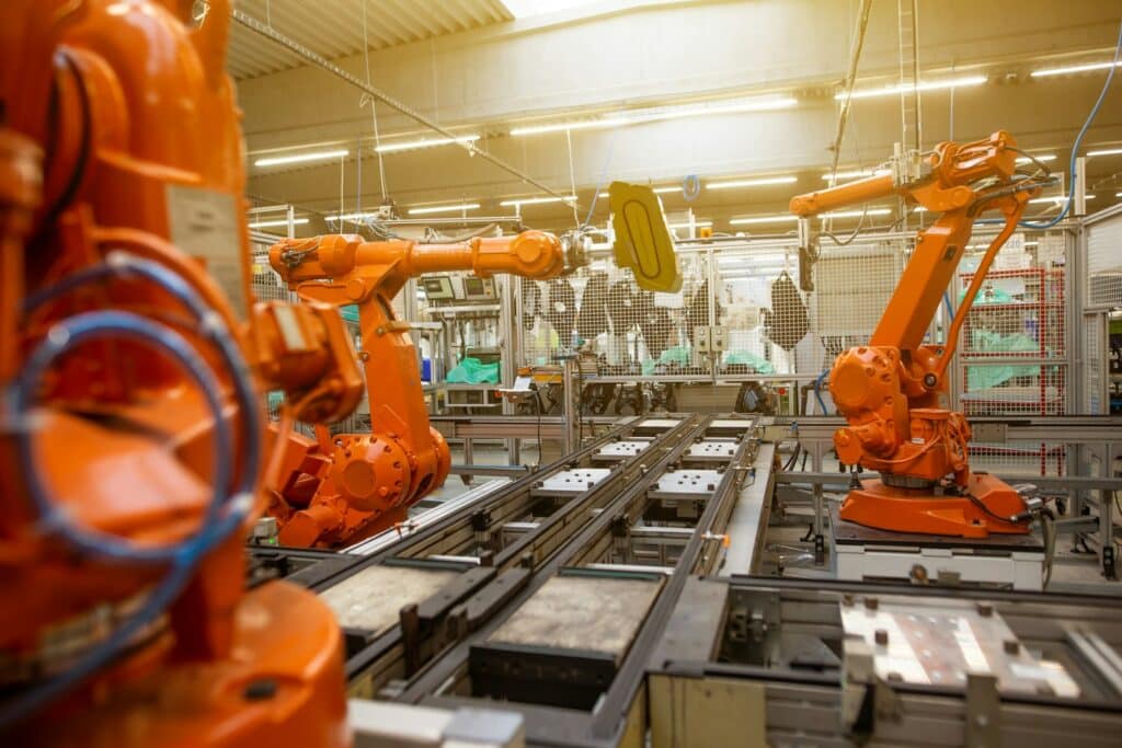 Orange robotic arms on an automated assembly line inside a large factory