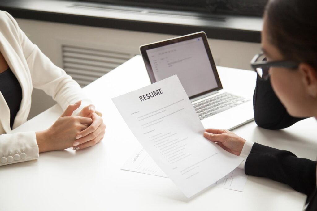 Technical recruiter reviewing a candidate's resume at a laptop during an interview, illustrating how recruiters use automation to work faster