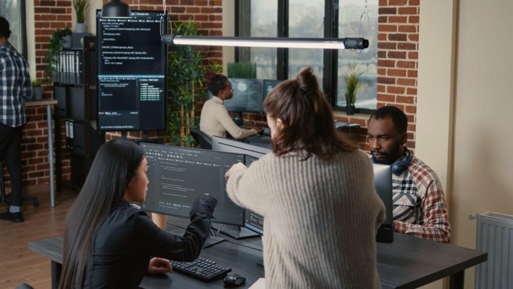 Software developers collaborating on AI code at their workstations in an office