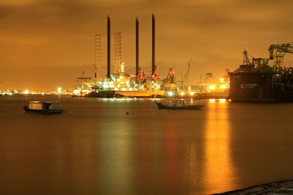 Oil refinery lit up at night across the water