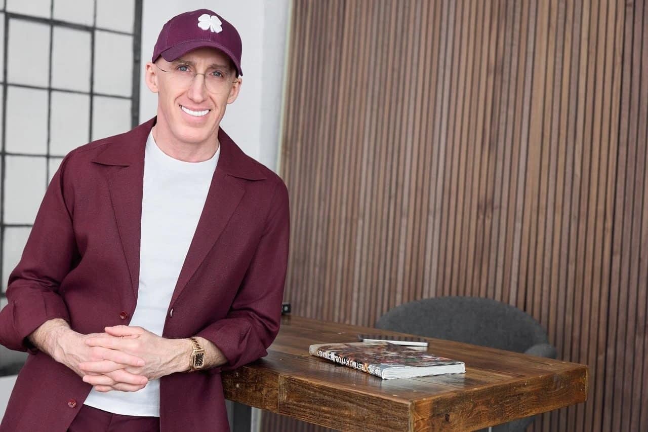 Uri Poliavich, co-founder of the Yael Foundation, smiling in a burgundy cap and jacket beside a wooden table