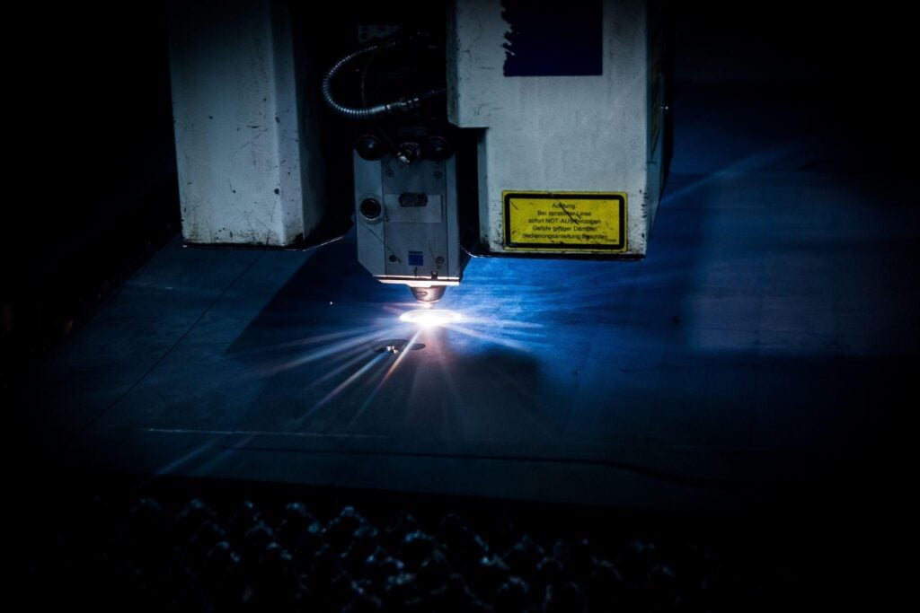 Automated laser cutting machine processing a metal sheet in a manufacturing facility